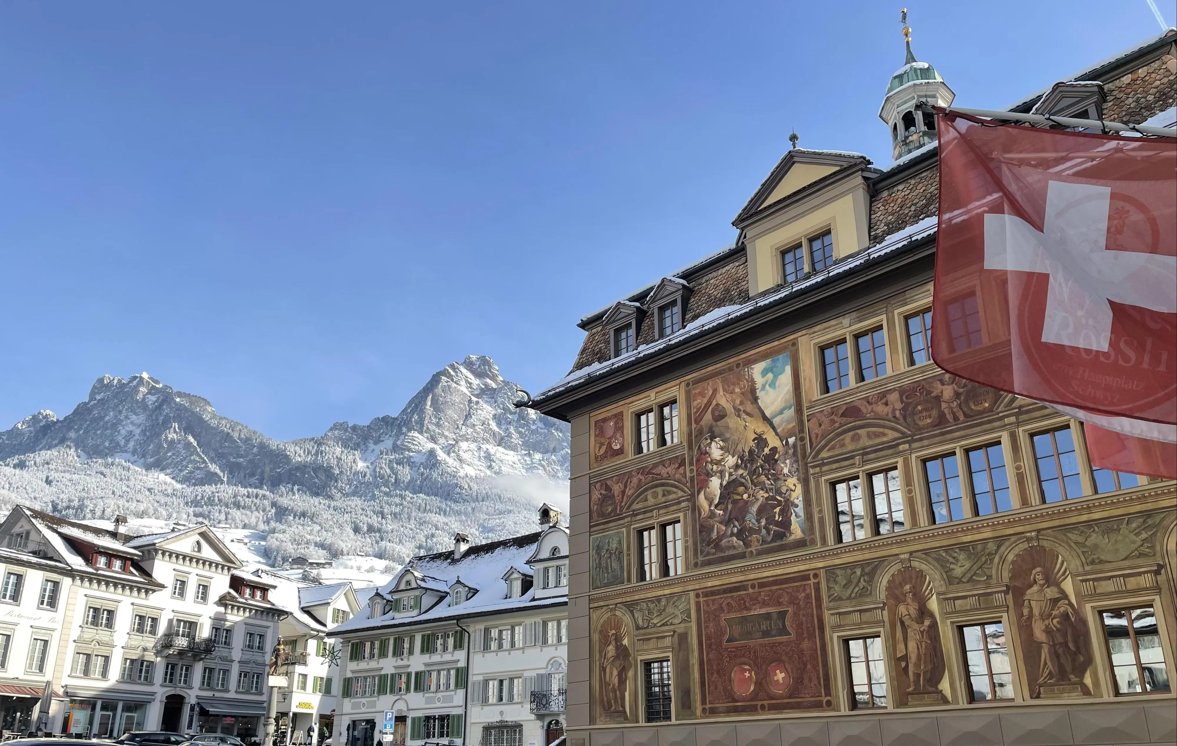 This is the historic town hall building in Schwyz.
It is a heritage-listed parliament and court building. It is known for the historicist façade painting by Ferdinand Wagner from 1891.

The house was built in 1590, burned down in 1642, then rebuilt, and renovated several times later. 
Even nowadays you can see traces of that fire of 1642 on the huge pillars of the current cantonal council chamber.

Its wikipedia article is only available in german:
https://de.wikipedia.org/wiki/Rathaus_(Schwyz)
...